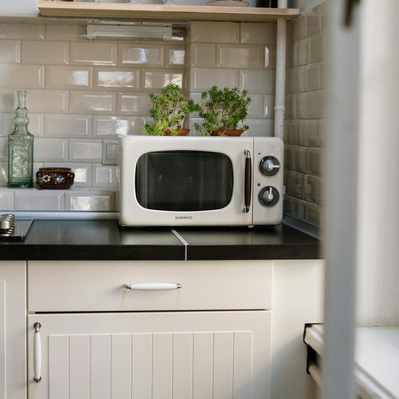 A cozy retro kitchen featuring a white vintage microwave and potted plants.